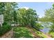 Lush backyard featuring manicured lawn, mature trees, and a lake view, creating a private outdoor oasis at 7815 Bamby Rd, Cumming, GA 30041