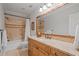 Bathroom with granite countertops, wooden cabinetry, large mirror, and tiled bathtub and shower at 7815 Bamby Rd, Cumming, GA 30041