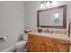 Stylish half bathroom features a wood vanity with granite countertop and decorative mirror at 7815 Bamby Rd, Cumming, GA 30041