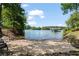 Sandy beach area overlooking the lake with a boat dock; lush trees and mature landscaping along the shoreline at 7815 Bamby Rd, Cumming, GA 30041