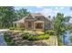 Attractive exterior showcasing stone accents, a well-manicured lawn, lush landscaping, and a glimpse of the lake at 7815 Bamby Rd, Cumming, GA 30041