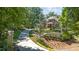 Scenic view of a home with a long driveway, lush greenery, and meticulous landscaping on a sunny day at 7815 Bamby Rd, Cumming, GA 30041