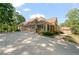 Exterior of a home showcasing a three-car garage, stone accents, and lush landscaping on a sunny day at 7815 Bamby Rd, Cumming, GA 30041
