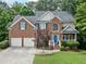 Traditional two-story brick home with a manicured lawn, blue door, and attached two-car garage at 117 Willow View Ln, Canton, GA 30114