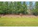 A lush green lawn with a stone wall, iron fence, and privacy trees bordering the backyard at 332 Rosshandler Rd, Suwanee, GA 30024