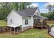 Back of a charming white home featuring a covered porch, stairs, and an outdoor water-pump system at 5745 Westwood Dr, Cumming, GA 30040