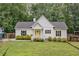 Bright white home featuring a yellow front door, black roof and shutters, set on a verdant lawn at 5745 Westwood Dr, Cumming, GA 30040