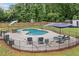 Inviting backyard pool area, surrounded by black metal fencing, patio furniture, and lush green trees at 5745 Westwood Dr, Cumming, GA 30040