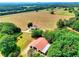 An aerial view showcases the home, barn, and large field surrounded by mature trees at 259 Hwy 11, Social Circle, GA 30025