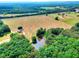 Aerial shot of homes surrounded by a lush green forest and large open field with a pond at 259 Hwy 11, Social Circle, GA 30025