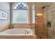 A luxurious bathroom featuring a large soaking tub, a glass-enclosed shower, and decorative tile work at 4721 W Lakeshore Dr, Acworth, GA 30101