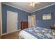 A cozy bedroom with blue walls, a ceiling fan, carpet, and a bed with a blue and white quilt at 4721 W Lakeshore Dr, Acworth, GA 30101