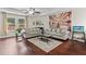 Sunlit living room with wood floors, neutral decor, large windows, and a view of the landscaped yard at 6330 Garden Cir, Douglasville, GA 30135