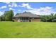 Back of brick home with screened porch and large grass backyard and mature trees at 3950 Chattahoochee Rd, Cumming, GA 30041