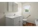Well-lit bathroom featuring a white vanity, toilet, and a window at 3950 Chattahoochee Rd, Cumming, GA 30041