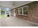 View of brick exterior wall and screened in sunroom from yard featuring ceiling fan and wood-look floor at 3950 Chattahoochee Rd, Cumming, GA 30041