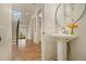 Hallway view showcasing a pedestal sink, round mirror, herringbone wood floors and stairs in the background at 4757 Lake Forrest Drive Northwest Dr, Atlanta, GA 30342