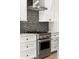 Close-up of the modern stove with an exhaust hood and patterned backsplash at 2333 Mason Dr # D26, Atlanta, GA 30316