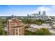 Aerial shot of a luxury condominium building with a city skyline backdrop, framed by lush greenery at 3180 Mathieson Ne Dr # 1401, Atlanta, GA 30305