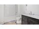 Bathroom features white tub with shower, dark vanity with quartz countertops, and modern fixtures at 530 Old Cobblestone Dr, Atlanta, GA 30350