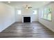 Inviting living room with a fireplace, natural light, modern ceiling fan, and beautiful wood floors at 62 Sheryl Way, Loganville, GA 30052