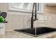 Close-up of the kitchen sink featuring granite countertops, tile backsplash, and modern fixtures at 1649 Beecher Sw St, Atlanta, GA 30310