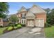 Two car garage features unique stone accents and is complemented by a paved driveway and manicured landscaping at 3250 Seven Oaks Dr, Cumming, GA 30041