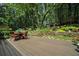 Enjoy this backyard featuring a deck, outdoor seating, stone retaining wall, lush greenery, mature trees and more at 7265 Hunters Branch Dr, Sandy Springs, GA 30328