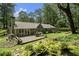 Lush backyard with mature trees, a wooden deck, stone patio, and manicured landscaping at 7265 Hunters Branch Dr, Sandy Springs, GA 30328