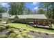 A view of the backyard pergola, hot tub, back of house with large windows, and landscaped flower beds at 7265 Hunters Branch Dr, Sandy Springs, GA 30328