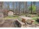 Backyard wooden picnic table and benches set up near shed and forest, with landscape lighting at 7265 Hunters Branch Dr, Sandy Springs, GA 30328