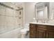 A small bathroom featuring wood cabinets, light tiling, glass enclosed shower with tub, and granite countertops at 7265 Hunters Branch Dr, Sandy Springs, GA 30328