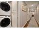 Bright hallway featuring stacked laundry with built in storage cabinets, and hardwood floors with elegant area rug at 7265 Hunters Branch Dr, Sandy Springs, GA 30328