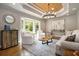 Stylish living room with hardwood floors, modern chandelier, and large bay window at 7265 Hunters Branch Dr, Sandy Springs, GA 30328