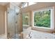 Bright primary bath boasts a glass shower, soaking tub, and a large window with backyard views at 206 Kingsley Way, Woodstock, GA 30188