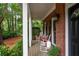 Inviting covered front porch featuring rocking chairs, black door, and lush landscaping at 206 Kingsley Way, Woodstock, GA 30188