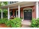 Welcoming front porch with rocking chairs and decorative plants; brick exterior and black door at 206 Kingsley Way, Woodstock, GA 30188