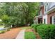 A beautifully landscaped walkway leads to a classic brick home, surrounded by lush greenery and mature trees at 206 Kingsley Way, Woodstock, GA 30188
