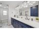Modern bathroom with dual vanity, sleek mirrors, glass-enclosed shower, and blue cabinets at 2885 Laurel Green Ct, Roswell, GA 30076