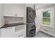 Well-organized laundry room with stacked washer/dryer and modern cabinetry and window at 2885 Laurel Green Ct, Roswell, GA 30076