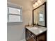 Bathroom featuring granite countertops, neutral walls, a window, and a decorative mirror at 5770 Bridleton Xing, Suwanee, GA 30024