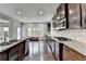 Bright, open kitchen with dark wood cabinets, stainless appliances, granite counters and view to living area at 5770 Bridleton Xing, Suwanee, GA 30024