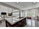 Large kitchen island with granite countertops in an open concept floorplan with hardwood floors and view to living room at 5770 Bridleton Xing, Suwanee, GA 30024
