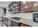 Close up of the dark wood cabinets and granite countertops featuring stainless steel microwave and gas cooktop at 5770 Bridleton Xing, Suwanee, GA 30024