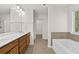 Bright bathroom featuring double sinks, wood cabinets, a large mirror, a tub, and a window at 2550 Trelipe Dr, Lawrenceville, GA 30044