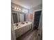 Bathroom features a double sink vanity, framed mirrors, and wood look flooring at 458 Vinings Vintage Cir, Mableton, GA 30126