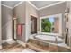 Bright bathroom featuring a large tub with a window view, a separate shower, and tile flooring at 5605 Copper Creek Pass, Cumming, GA 30040