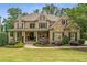 Stately brick home with a manicured front lawn, elegant landscaping, and a welcoming covered front porch at 5605 Copper Creek Pass, Cumming, GA 30040