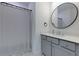 Bathroom with a large, round mirror over the vanity, and shower with curtain at 302 Boxwood Ln, Roswell, GA 30075