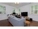 Bright and open living room with a large couch, desk, and natural light from shuttered windows at 302 Boxwood Ln, Roswell, GA 30075